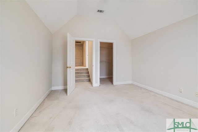 unfurnished bedroom with lofted ceiling, visible vents, a spacious closet, and baseboards