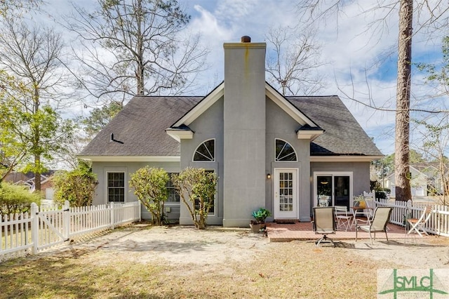 rear view of property with a fenced backyard, a chimney, roof with shingles, a patio area, and stucco siding