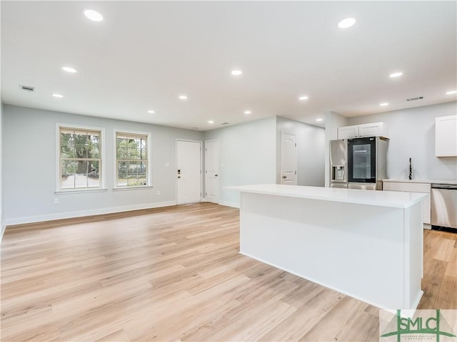 kitchen with light hardwood / wood-style flooring, a kitchen island, stainless steel appliances, and white cabinetry