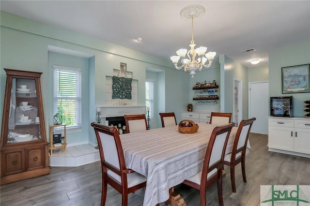 dining area featuring dark hardwood / wood-style flooring, a fireplace, and a notable chandelier