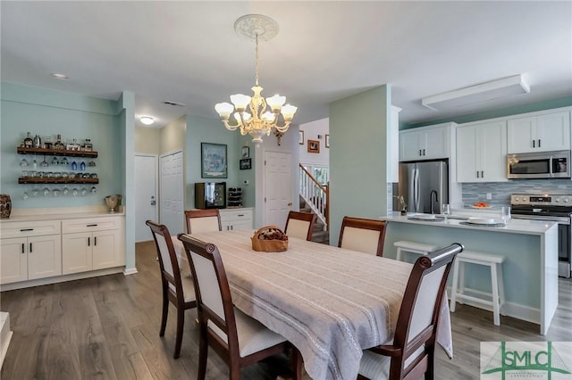 dining area featuring dark wood-type flooring, sink, and a notable chandelier