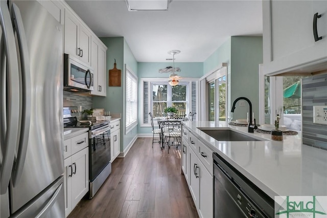 kitchen with stainless steel appliances, tasteful backsplash, decorative light fixtures, white cabinets, and sink