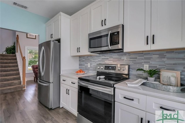 kitchen featuring decorative backsplash, white cabinets, dark hardwood / wood-style floors, and stainless steel appliances