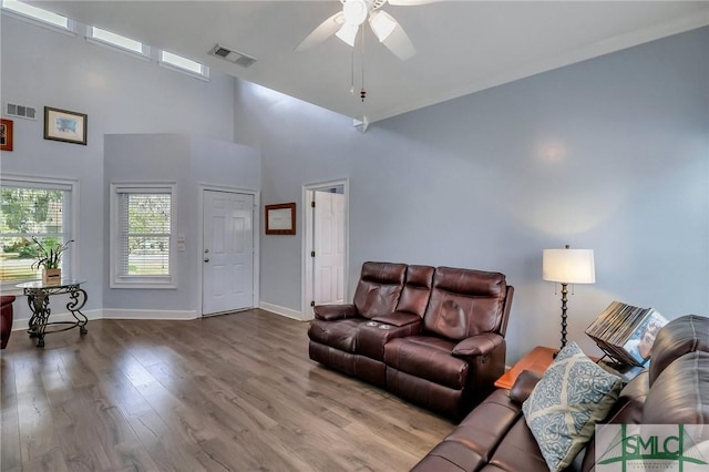 living room featuring ceiling fan, a high ceiling, and wood-type flooring