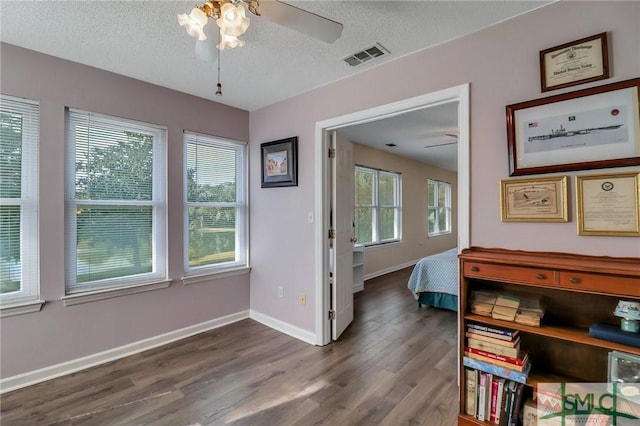 bedroom featuring ceiling fan, dark wood-type flooring, and a textured ceiling