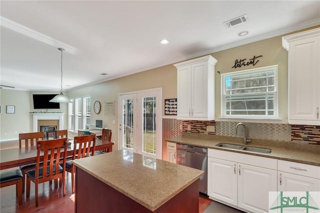 kitchen featuring dishwasher, backsplash, a fireplace, and a sink