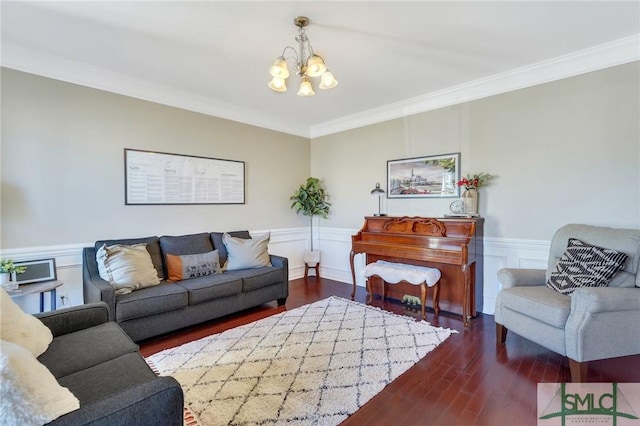 living room featuring dark wood-style floors, a wainscoted wall, ornamental molding, a chandelier, and a decorative wall