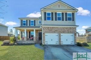 view of front of home with a garage, covered porch, and a front yard