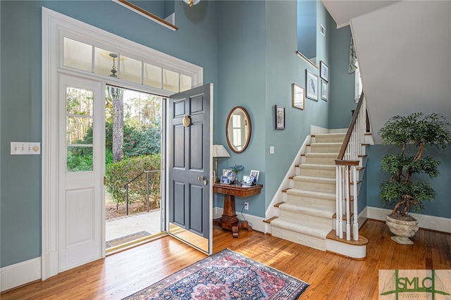 entrance foyer with a towering ceiling and wood-type flooring