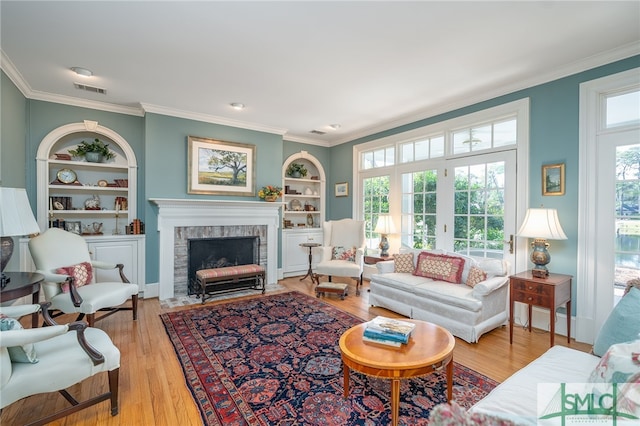 living room featuring a brick fireplace, built in features, french doors, and light wood-type flooring