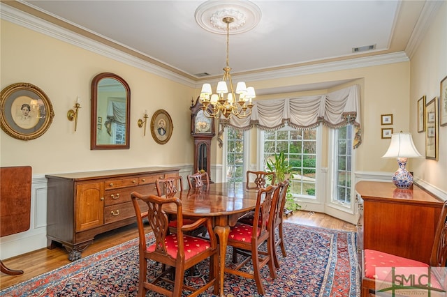 dining space with light hardwood / wood-style flooring, ornamental molding, and a notable chandelier