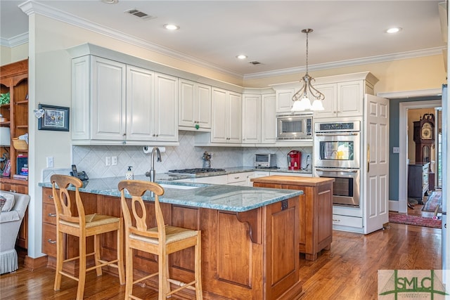 kitchen featuring stainless steel appliances, pendant lighting, white cabinets, and light stone counters