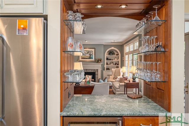 kitchen featuring stainless steel fridge, beverage cooler, crown molding, light stone counters, and built in shelves