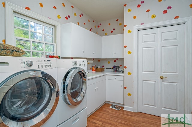 laundry area with washing machine and dryer, cabinets, and light wood-type flooring