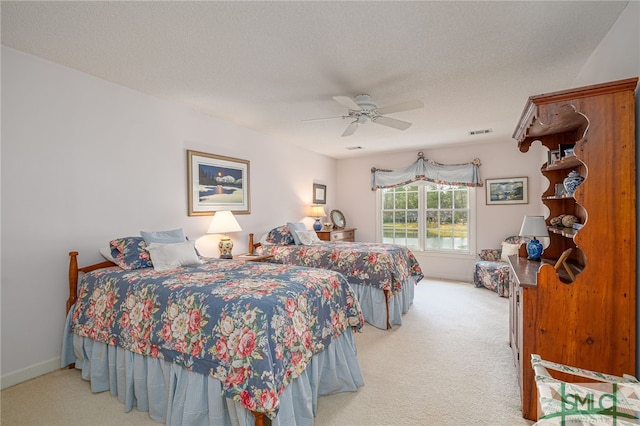 bedroom with ceiling fan, carpet, and a textured ceiling