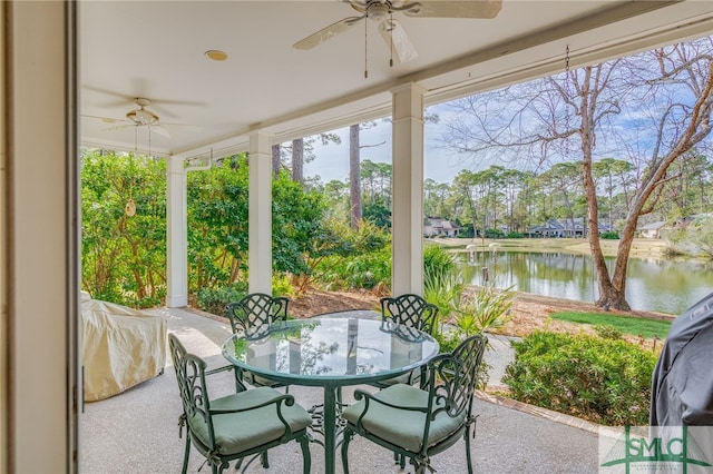 sunroom with ceiling fan and a water view