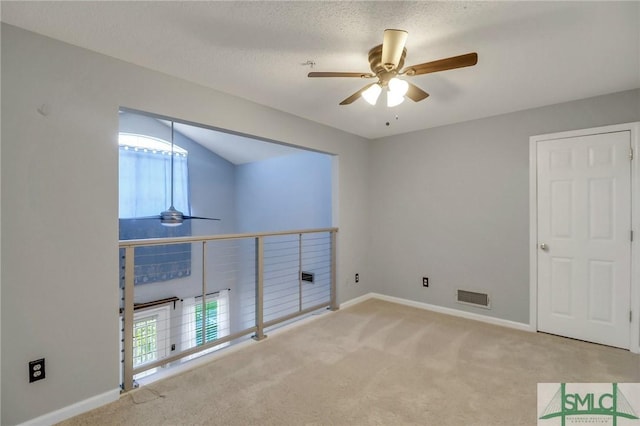 carpeted spare room with ceiling fan, a textured ceiling, and vaulted ceiling