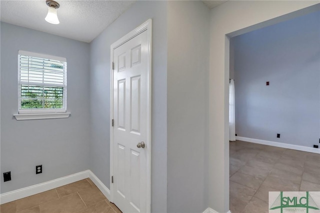 clothes washing area featuring a textured ceiling and light tile patterned flooring