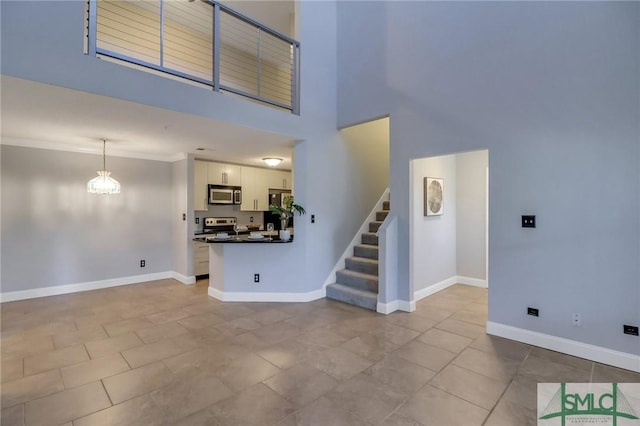 interior space featuring a chandelier, ornamental molding, a towering ceiling, and light tile patterned flooring