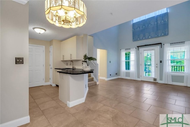 kitchen featuring white cabinetry, kitchen peninsula, light tile patterned flooring, a chandelier, and sink