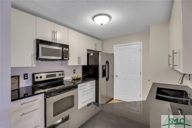 kitchen featuring white cabinets, appliances with stainless steel finishes, sink, and a textured ceiling