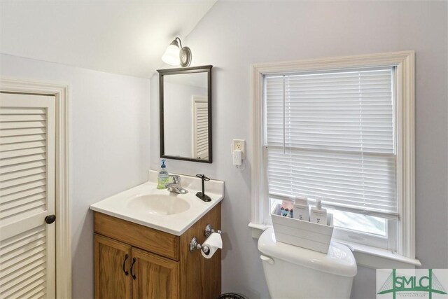 bathroom with toilet, lofted ceiling, and vanity