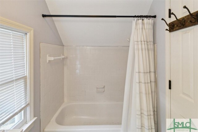 bathroom with lofted ceiling and shower / bath combination with curtain