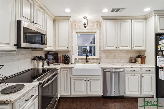 kitchen featuring decorative backsplash, sink, light stone counters, and stainless steel appliances