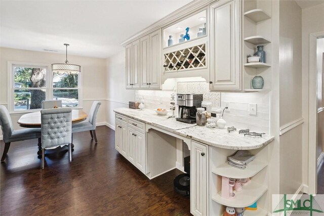 kitchen featuring light stone counters, white cabinets, tasteful backsplash, and hanging light fixtures