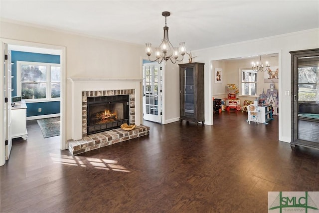 living room featuring a brick fireplace, a chandelier, a wealth of natural light, and dark hardwood / wood-style floors