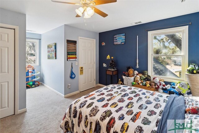 bedroom with ceiling fan, light colored carpet, and multiple windows