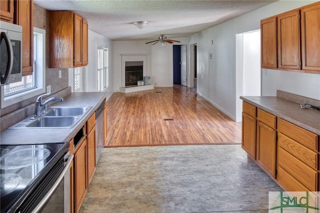 kitchen with light hardwood / wood-style floors, ceiling fan, appliances with stainless steel finishes, a textured ceiling, and sink