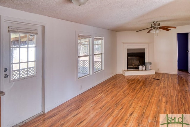 unfurnished living room featuring wood-type flooring, a textured ceiling, and ceiling fan