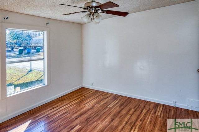 unfurnished room featuring a wealth of natural light, a textured ceiling, and hardwood / wood-style flooring