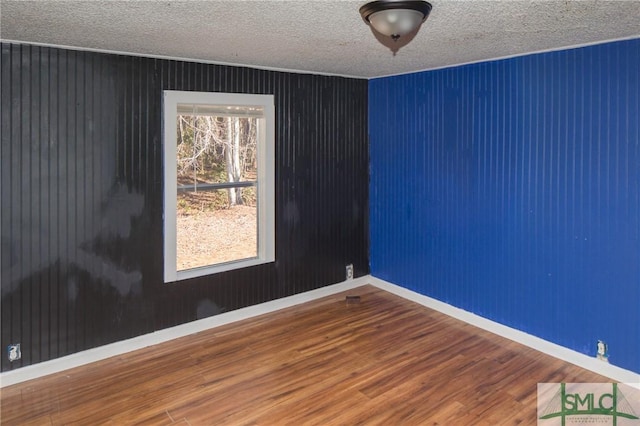 spare room featuring a textured ceiling and wood-type flooring