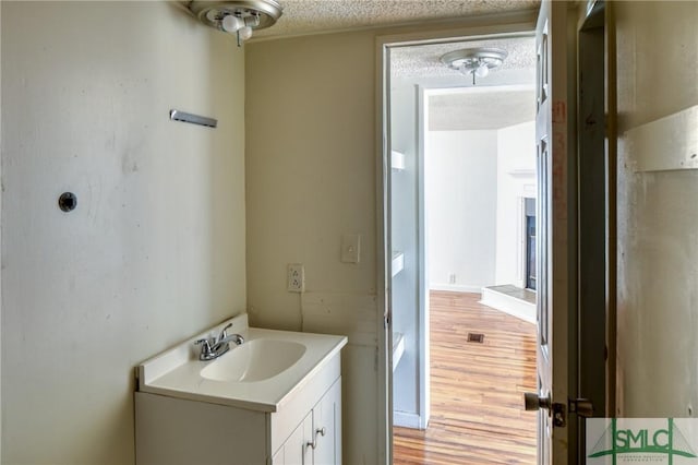 bathroom with vanity, wood-type flooring, and a textured ceiling