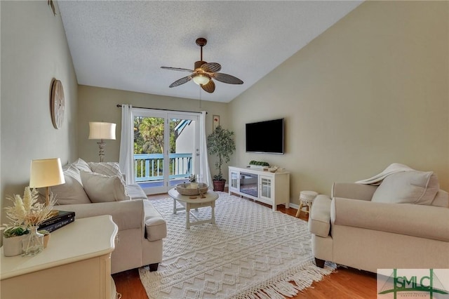 living room with ceiling fan, wood-type flooring, lofted ceiling, and a textured ceiling