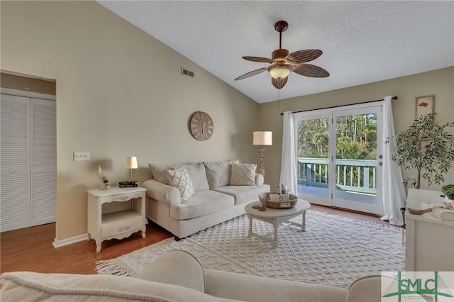 living room featuring vaulted ceiling, ceiling fan, a textured ceiling, and hardwood / wood-style floors