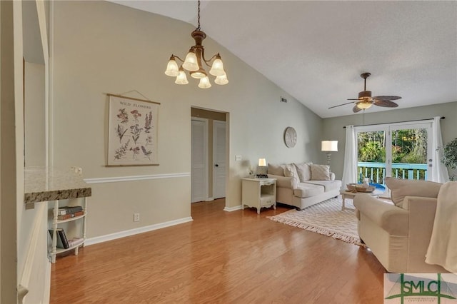 living room with ceiling fan with notable chandelier, wood-type flooring, a textured ceiling, and vaulted ceiling