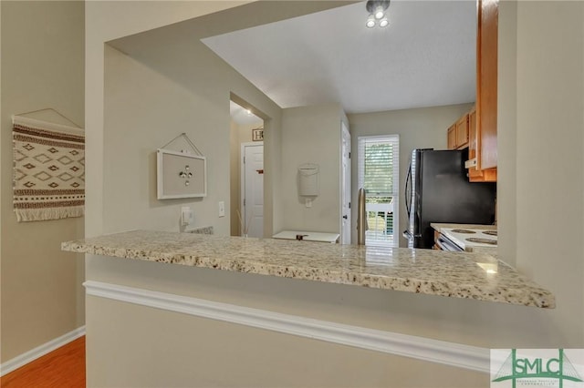 kitchen featuring black refrigerator, kitchen peninsula, white electric stove, and hardwood / wood-style floors