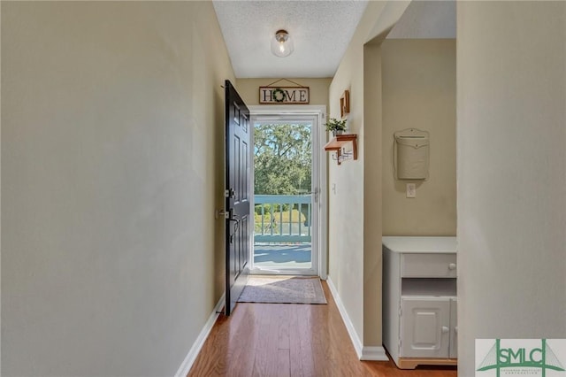 doorway to outside with light wood-type flooring and a textured ceiling