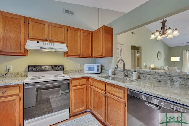 kitchen featuring white appliances, vaulted ceiling, a chandelier, light stone counters, and sink