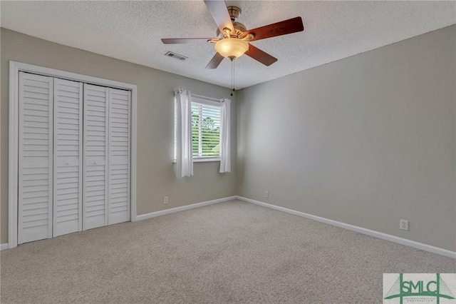 unfurnished bedroom featuring ceiling fan, a closet, carpet floors, and a textured ceiling