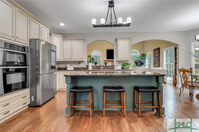 kitchen with hanging light fixtures, a chandelier, a kitchen bar, and stainless steel appliances