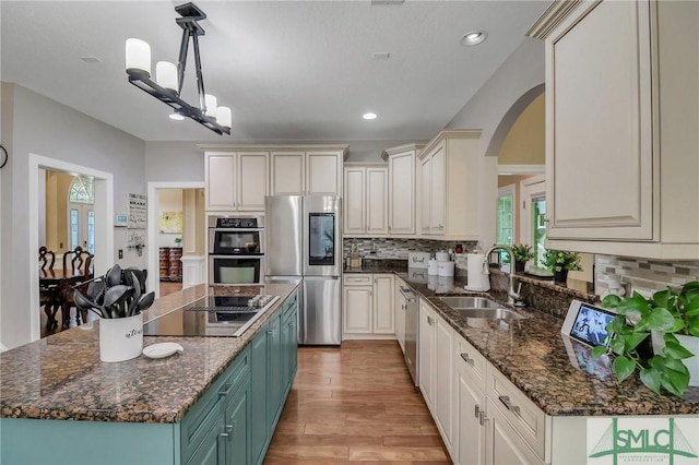 kitchen featuring appliances with stainless steel finishes, a kitchen island, decorative light fixtures, an inviting chandelier, and sink