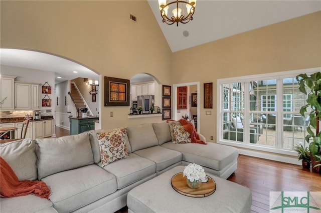 living room featuring high vaulted ceiling, wood-type flooring, and a chandelier