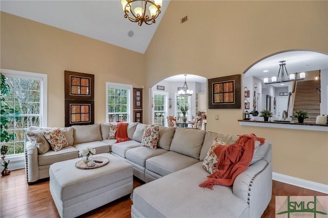 living room featuring high vaulted ceiling, hardwood / wood-style flooring, and a chandelier