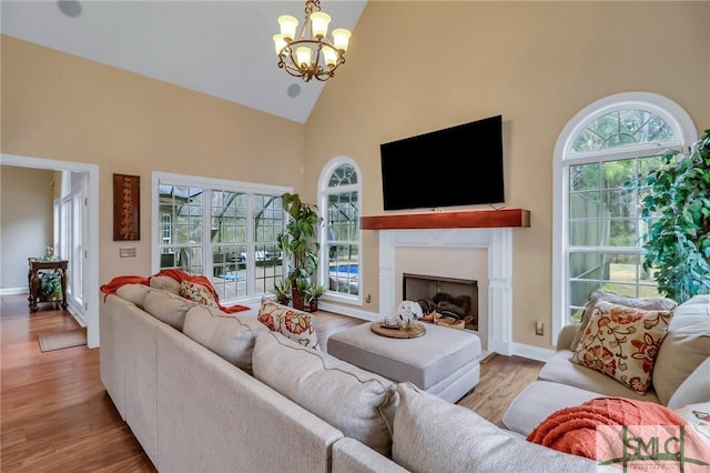 living room with high vaulted ceiling, a notable chandelier, and light hardwood / wood-style flooring