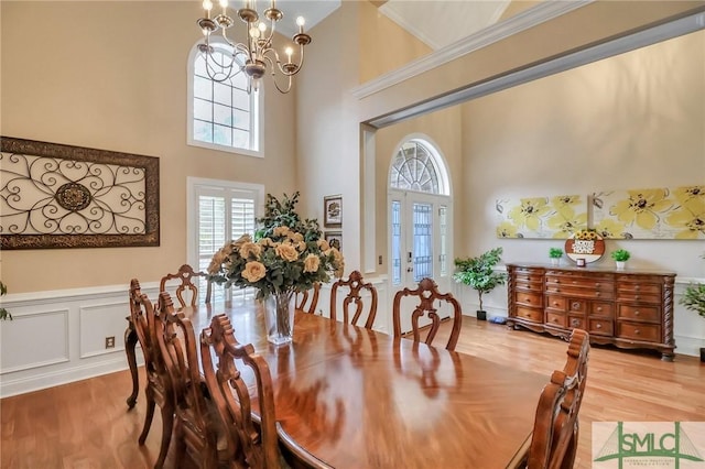 dining area featuring a notable chandelier, crown molding, a towering ceiling, and hardwood / wood-style floors