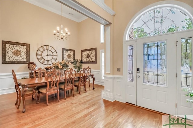 entryway with an inviting chandelier, ornamental molding, and light hardwood / wood-style floors